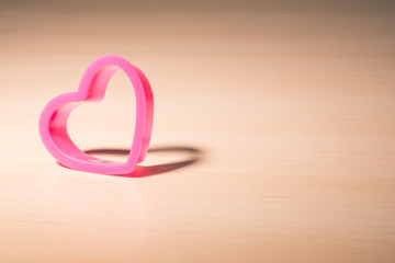 pink heart on wood table with shadow
