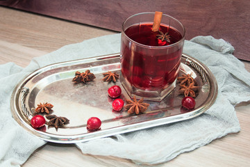 mulled wine with cherries, cinnamon and star anise in a glass on vintage silver tray