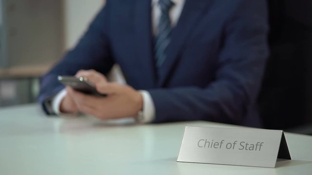 Male chief of staff texting on smartphone, using gadget for communication