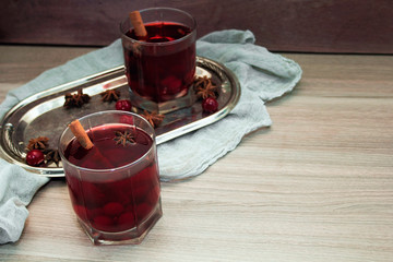 mulled wine with cherries, cinnamon and star anise in a glass on vintage silver tray
