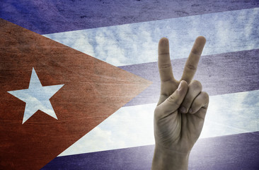 Victory symbol - two fingers against background of Cuba flag