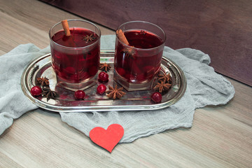 two glasses of mulled wine with cherries, cinnamon and star anise for lovers on silver vintage tray with red heart. concept for a romantic anniversary, Valentine's day