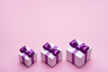 Beautiful gifts with satin bows on a pink background