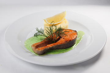 Salmon Steak with mashed potatoes on a plate isolated white background pesto