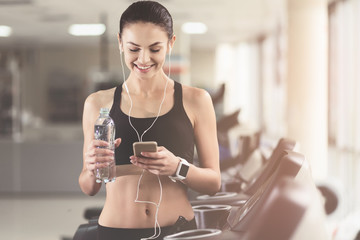Athletic girl using smartphone in a gym