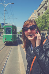 Fototapeta premium Using cellphone with defocused city transportation station.