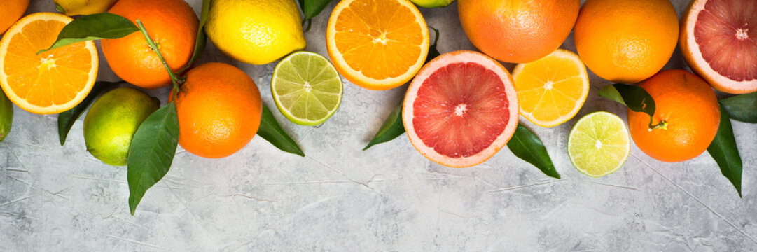 Fototapeta Citrus fruit on grey concrete table. Food background. Healthy eating. Long banner format good for web.