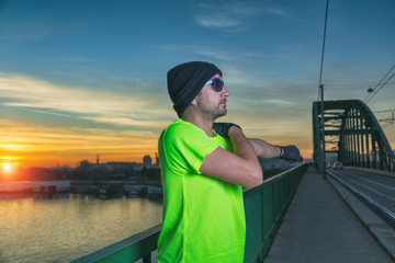 Urban jogger stretching on the bridge at sunset / sunrise.