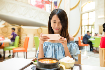Woman taking photo on cellphone in restaurant