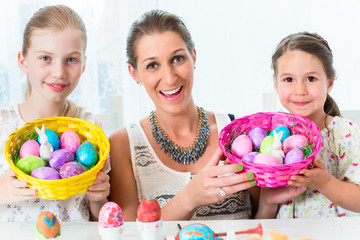 Familie mit Mutter und Kind färbt Eier zu Ostern