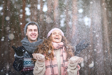 Winter Love Story, a young couple walking and having fun in a winter forest under heavy snow, catching snowflakes