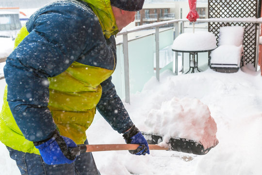 Man shoveling the show on the terrace after heavy snowfall