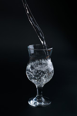 Water poured from the bottle into a transparent glass