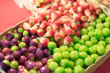 Colorful Thai miniature fruit confection in soft focus with warm fall color.