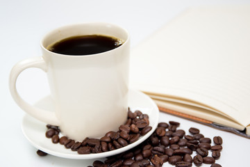 Coffee cup and leather notebook close up on white background.