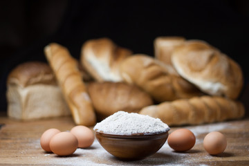 different bread on the wooden table, flour, sackcloth, bowl