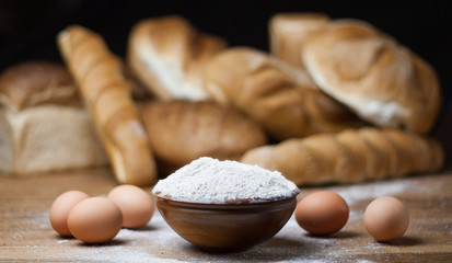 different bread on the wooden table, flour, sackcloth, bowl