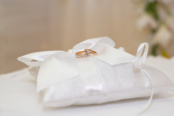 Wedding rings lying on white cushion