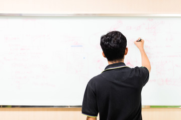 office, business, people and education concept - Asian teacher with marker writing about engineering on white board in soft focus.