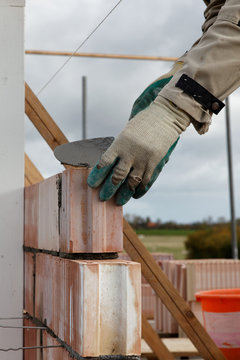 close up of bricklayer mason placing a stone outdoors