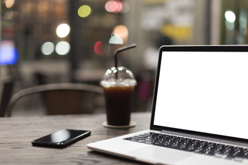 Abstract : Alone , Black coffee telephone and blank laptop place on the wooden table with soft focus in coffee shop and blurred background.