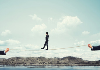 Obraz premium Business concept of risk support and assistance with man balancing on rope