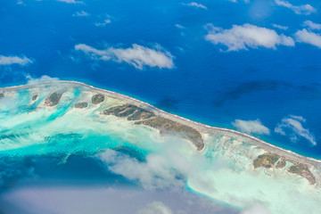 Aerial view of the island with clouds, reef and lagoon. Island n