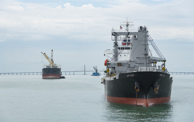 Obraz premium A landscape image of a cargo ship sailing past the Penang Bridge.