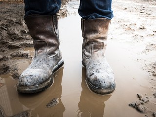 Dirty brown boots on the mud when raining