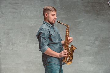 Happy saxophonist with sax over gray background