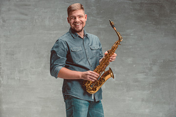 Fototapeta na wymiar Happy saxophonist with sax over gray background