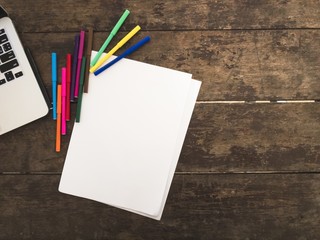 Laptop and marker on the wooden table with space on right side.