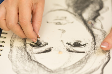 Young girl doing a sketch of natural charcoal on paper