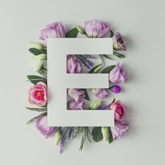 Creative layout with colorful flowers, leaves and letter E. Love
