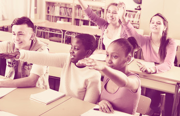 Fototapeta premium Group of happy school pupils raise their hands up