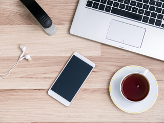 Wooden table with smartphone and Cup of tea, Desk. The view from the top