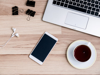 Wooden table with smartphone and Cup of tea, Desk. The view from the top