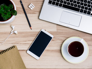 Wooden table with smartphone and Cup of tea, Desk. The view from the top