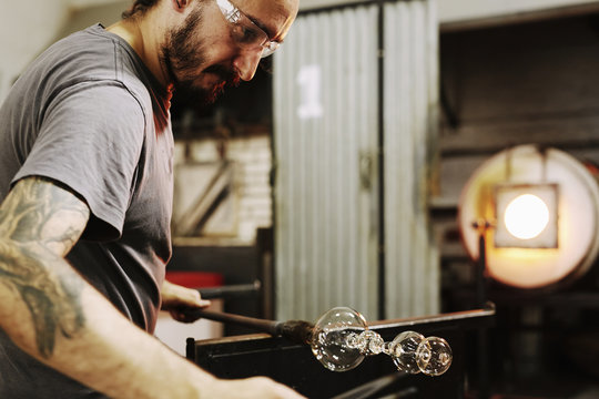 Glassblower shaping blown glass