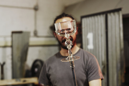 A man in a workshop holding up a goblet