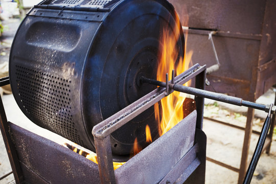 Chestnuts roasting in a large metal cylinder over flaming coals. 