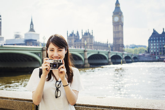 Young Japanese woman enjoying a day out in London, standing on the Queen's Walk by the River Thames.