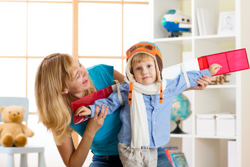 Child boy dressed like a pilot with toy wings playing at home