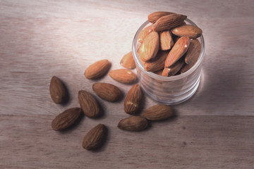 Almonds in brown bowl on wooden background
