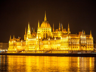 Fototapeta na wymiar Night view of illuminated historical building of Hungarian Parliament, aka Orszaghaz, with typical symmetrical architecture and central dome on Danube River embankment in Budapest, Hungary, Europe. It