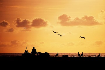Fototapeta na wymiar fisherman silouhette on the beach at sunset