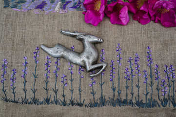 The deer jumps on an embroidery of flowers of a lavender