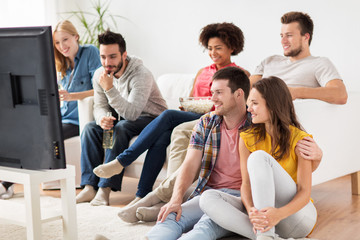 happy friends with popcorn watching tv at home