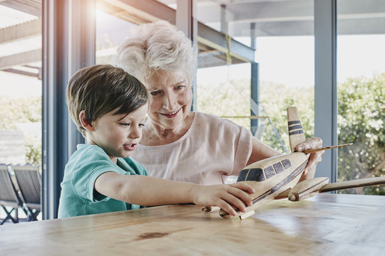 Grandson and grandmother playing with toy airplane