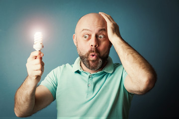Bearded middle-aged  man holding shinny lightbulb in his hand